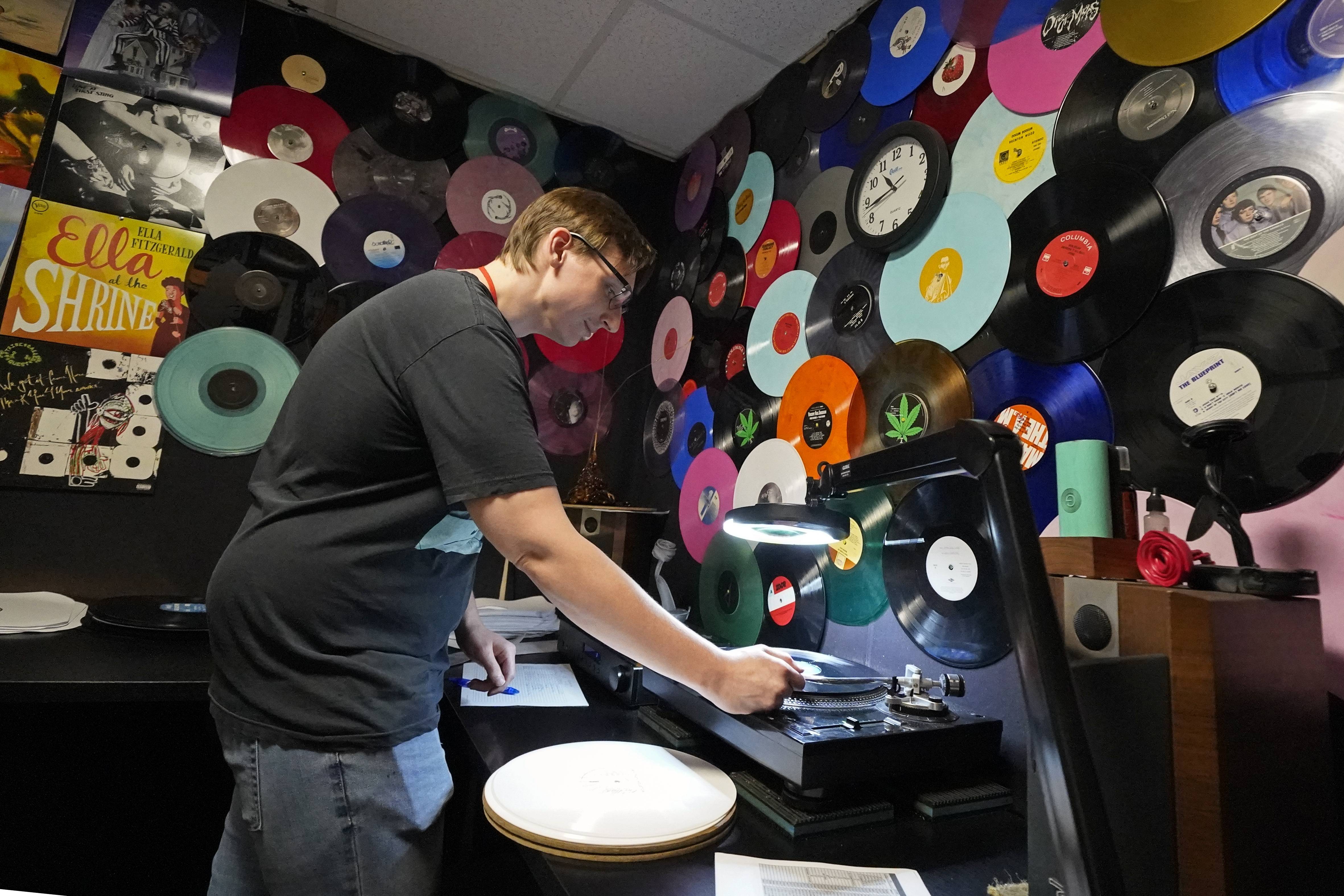 Tyler Bryant listens to finished record albums for flaws in a quality control room at the United Record Pressing facility Thursday, June 23, 2022, in Nashville, Tenn. The arrival of the compact disc nearly killed off record albums. Four decades later, with resuscitated record album sales producing double-digit growth, manufacturers are rapidly rebuilding an industry to keep pace with sales that topped $1 billion last year.