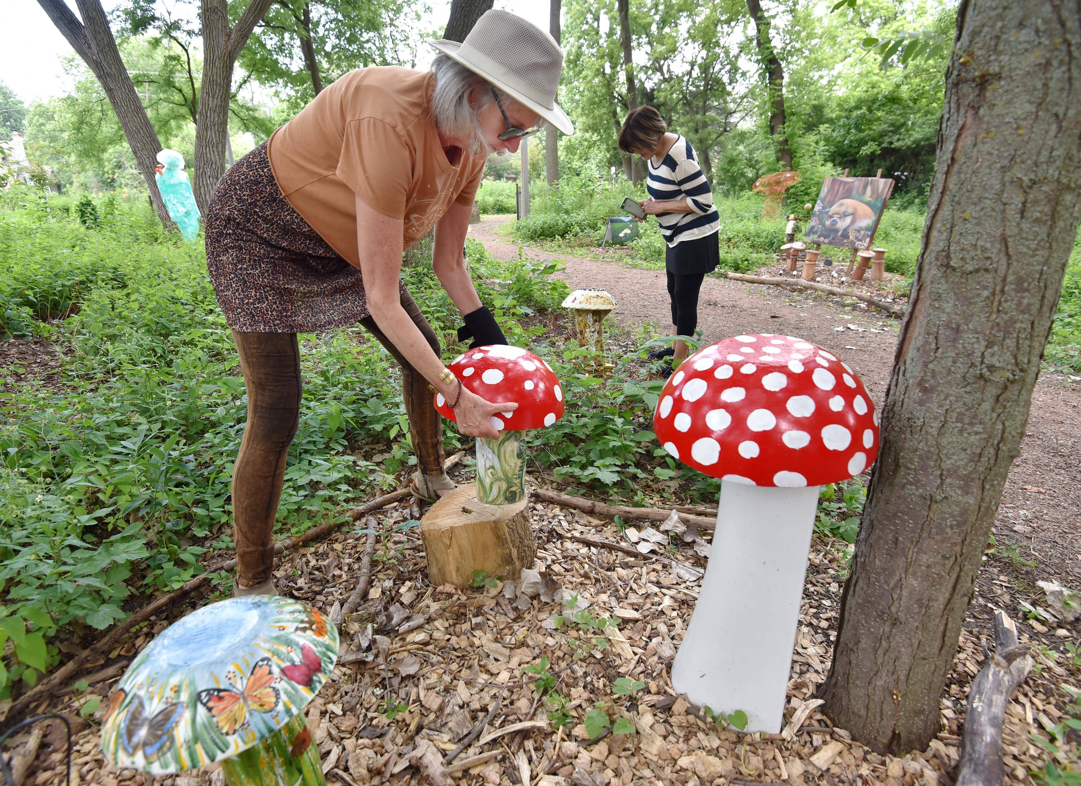 Kate Tully installs the cement top to her mushroom art at Isaac Walton Park in Prospect Heights as artist June Nichols of Rolling Meadows takes pictures of her pieces. They are part of The Sunflower Project group that displays work every summer in a city park.