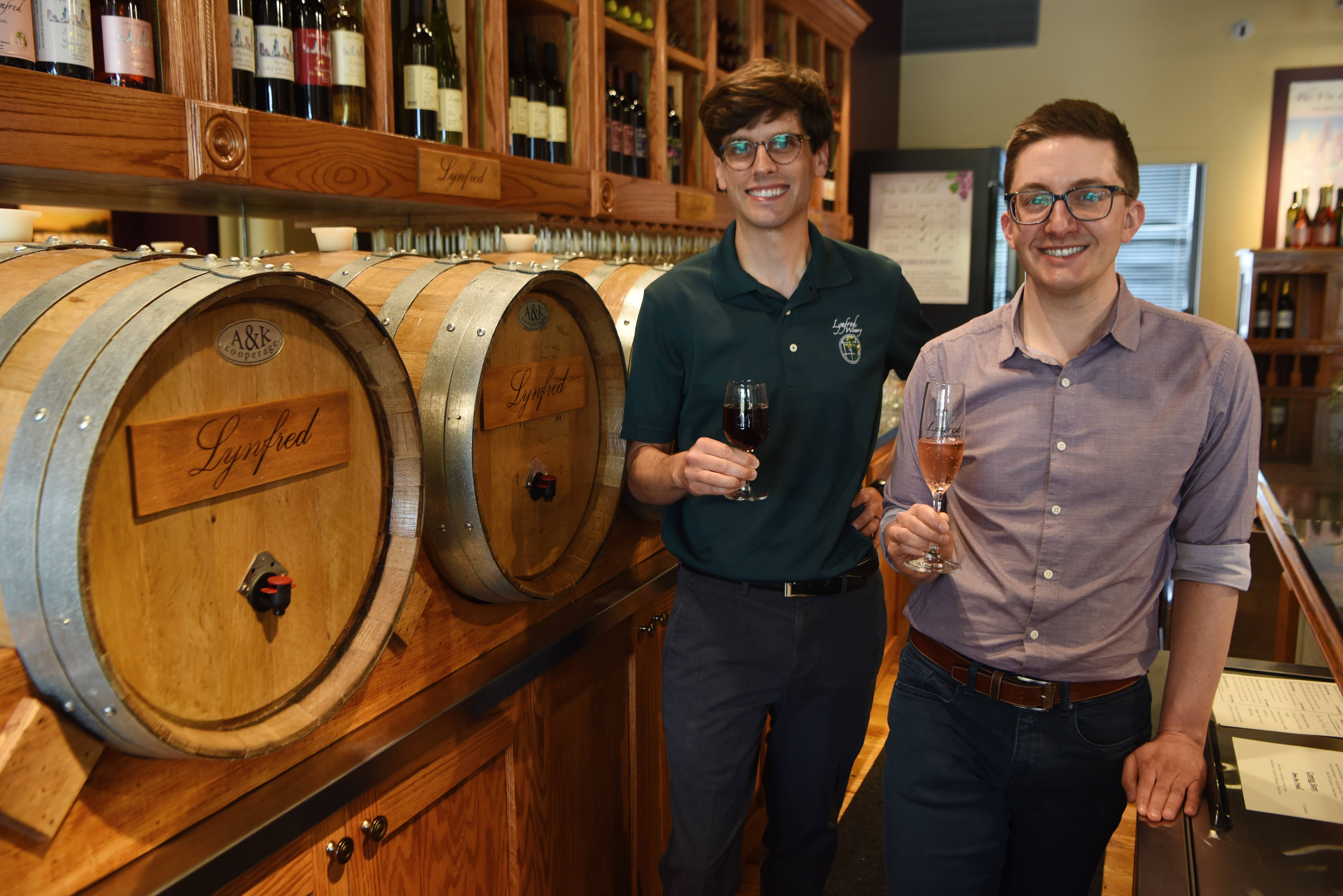 Lynfred Winery's John Elder and Matt Phillips hold glasses of wine at the winery's new location in Highland Park.