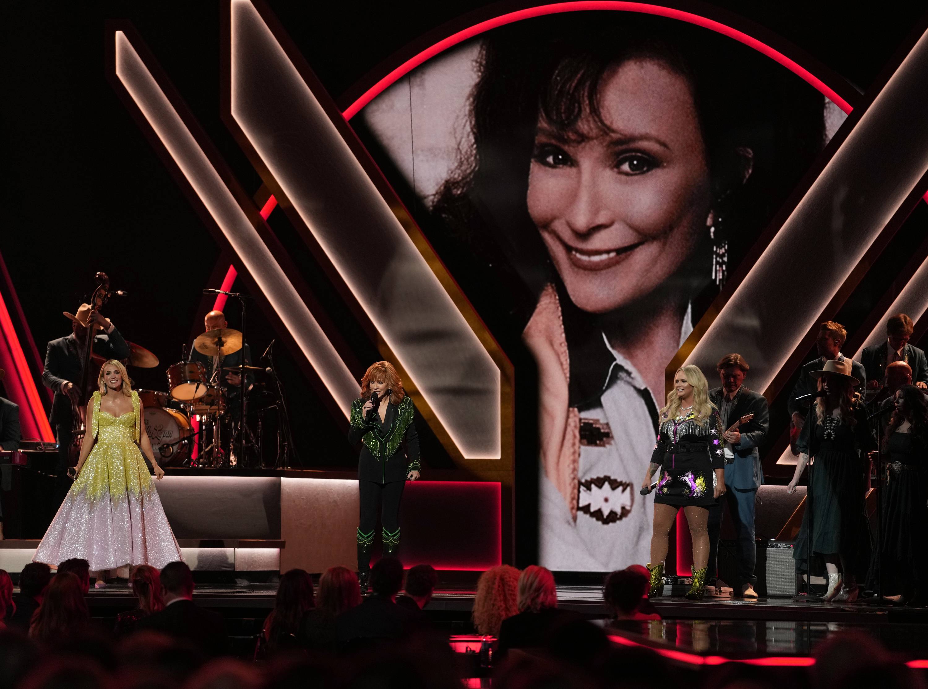 Carrie Underwood, from left, Reba McEntire and Miranda Lambert perform in honor of the late singer Loretta Lynn, pictured on screen, during the 56th annual CMA Awards on Wednesday at the Bridgestone Arena in Nashville, Tenn.