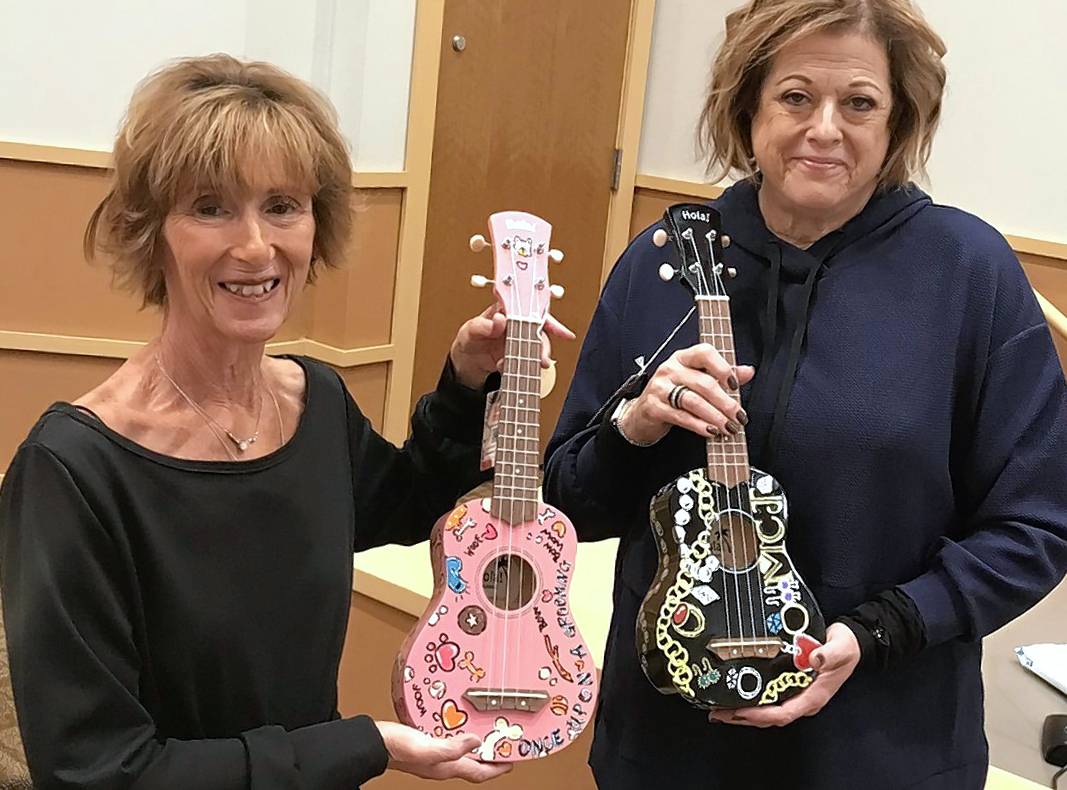 Linda Rosen, left, director of the 75-member BG Singers choral group, and Cathy Novak, president of the Friends of the Parks Foundation, show off two of the ukuleles being put in the hands of children in hospitals as part of music therapy.